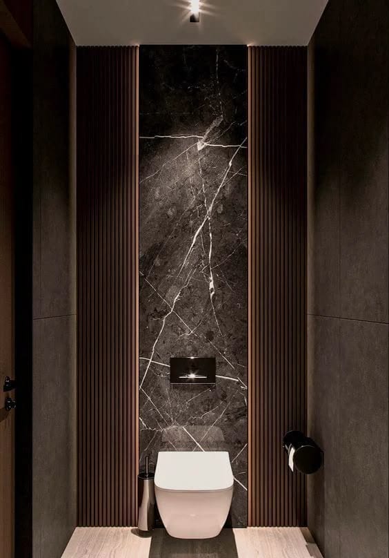 Baño contemporáneo con inodoro suspendido, mármol oscuro y lambrines de madera retroiluminados — showroom A.MODO
